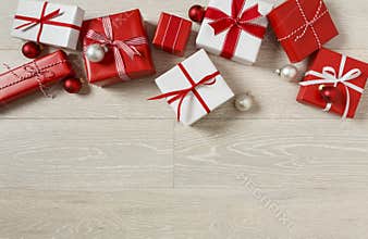 Christmas gifts presents on rustic wood background. Simple, red and white gift boxes festive holiday border.