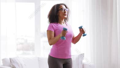 African woman exercising with dumbbells at home