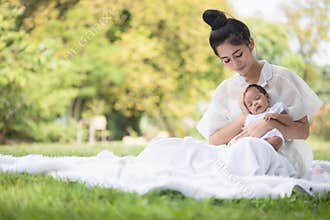 Young Asian mothers or single mom are smiling and  hugging newborn babies. Family doing activities and relaxing in the park.