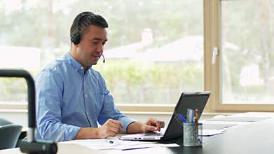 Man with headset and laptop working at home
