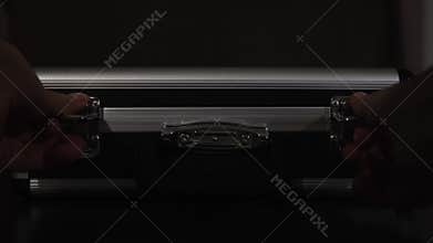 Close up of female hands opening silver metal suitcase with locking system. Concept. Opening aluminum carrying case to