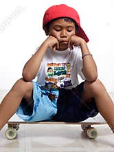 Sad little boy sitting on his skateboard