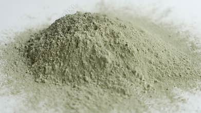 Close up green clay powder rotates on white background