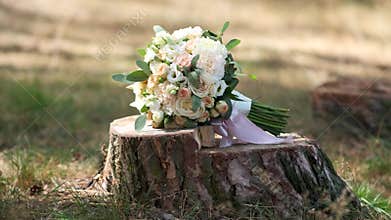Beautiful bouquet of roses in pink tones lies on a tree stump. Wedding decor