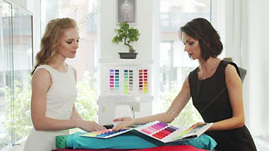 A client and a seamstress choose a fabrics in a tailor shop.