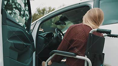 Young disabled person getting out from the car in her wheelchair.