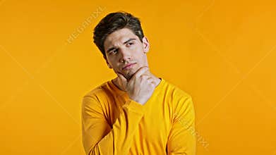 Thinking man looking up and around on yellow background. Worried contemplative face expressions. Handsome male model.