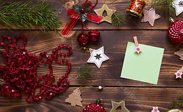 Christmas flat lay of red balloons and wooden stars and clothespins on a dark background with a square sheet for notes in the cent