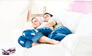 Resting couple lying on sofa after painting a room