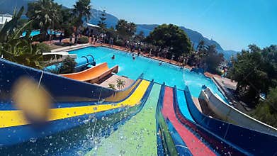 POV of person riding on colorful slide in aqua park at tropical resort