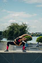 Girl doing exercises and twine on a sports field by the lake