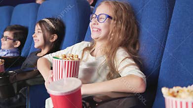 Group of smiling kids sitting in comfortable chair at cinema