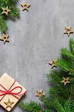 Christmas presents with red ribbon on gray background in a frame made of fir branches with star. Flat lay, top view. Christmas