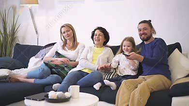 Happy family is sitting on couch together and watching comedy film good quality on tv.