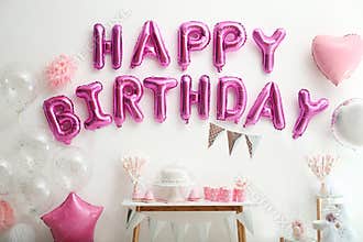 Phrase HAPPY BIRTHDAY made of balloon letters on white wall