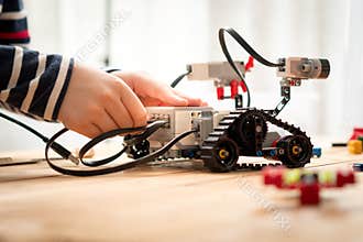 STEM Education, hands of preteen / teenage boy assemble, learn to program and test his robot for school project