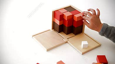 Child hands using a cube of wooden binomial belonging to Montessori pedagogy