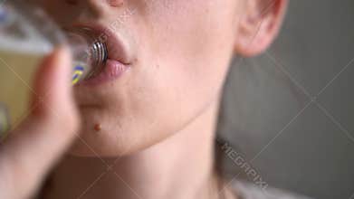 Close up of girl lips drinking from glass bottle. Lemonade, cider, beer, kombucha