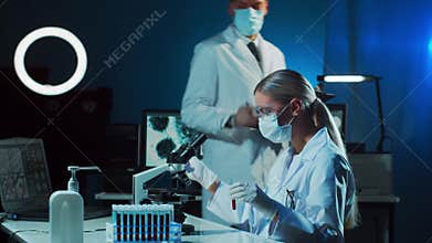 Medical scientists working in lab. Doctor teaching intern to make blood analyzing research. Laboratory tools: microscope