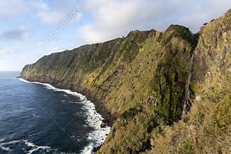 Landscape image of Cascata da Ponta do Arnel waterfall showing the wild green cliffs of the eastcoast of SÃ£o Miguel island on the