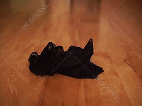 A woman in black shoes throws lace lingerie on the floor and leaves.