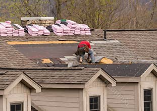 Roofing contractor removing the old shingles from a roof ready for reroofing