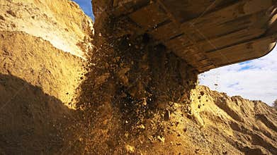 Excavator in action at the construction site. Stock footage. Bottom view of excavator flipping the bucket of yellow