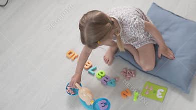 A beautiful little girl learns to count in a playful way