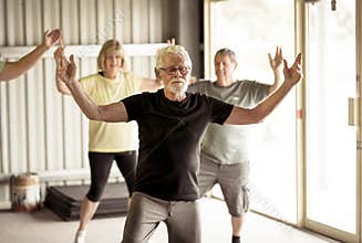 Group of elderly senior people practicing Tai chi class in age care gym facilities
