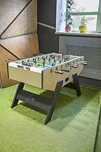 Children`s game - table football with figures of football players of both teams in a wooden box in the playroom for teenagers.