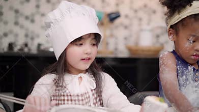 Slow motion - Group of children baking cake together in classroom, Multi-ethnic young boys and girls happy making dessert cooking