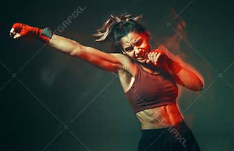 Cool girl fighter with relief abs makes jab in studio in neon light. Sport and motivation concept. Long exposure shot