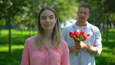 Man bringing girl bunch of flowers, annoyed lady rolling eyes, unrequited love