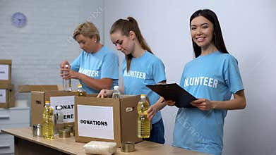 Social center workers preparing food donation boxes making notes, volunteering