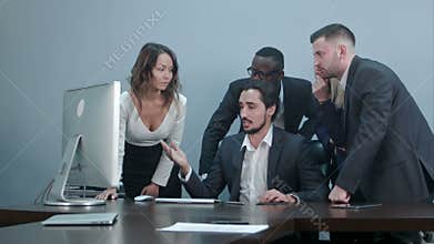 Group of multiracial business people around the conference table looking at laptop computer and talking to one another