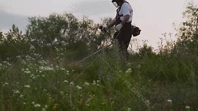 View from down of male gardener in process of cutting grass