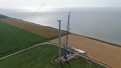 Aerial footage of the construction of a wind turbine with cranes and parts