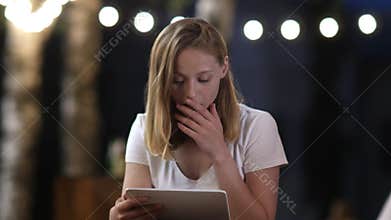 Worried woman is checking tablet online content. Shocked emotion.