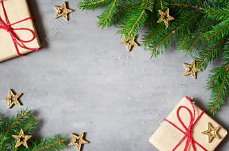 Christmas presents with red ribbon on gray background in a frame made of fir branches with star. Flat lay, top view. Christmas
