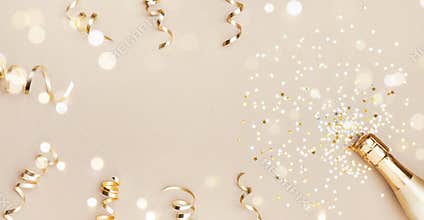 Champagne bottle with confetti stars, bokeh decoration and party streamers on golden background. Christmas flat lay