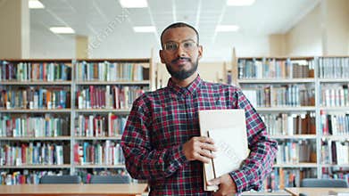 Portrait of African American student walking in university library with books