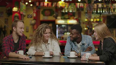 Happy multiracial young people friends talking laughing at group meeting sharing cafe table, diverse students drinking