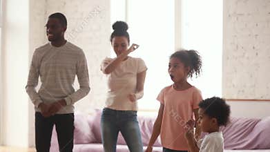 Happy Africam parents and cute funny kids dancing at home
