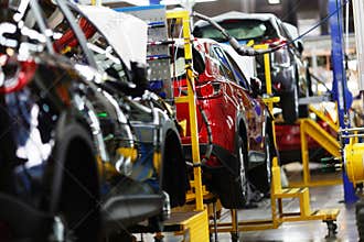 A red crossover is standing on a transport tape at a car factory. Car manufacturing.