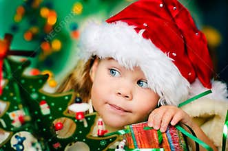 Happy small girl in Santa's hat has a Christmas