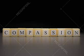 The word COMPASSION written on wooden cubes isolated on a black background