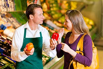 Woman in supermarket and shop assistant
