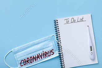 Face mask, thermometer and notebook with to do list for actions in case of coronavirus disease. Corona virus concept