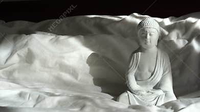 White buddha statue with sunlights on the bed, interior design detail in modern home