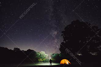woman camping with tent in forest at night with starry sky